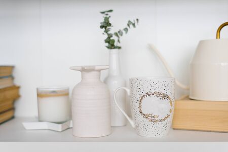 Mug, vase and candle on the shelf in the living room in white and beige colorsの写真素材