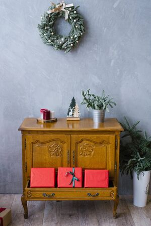 Wooden chest of drawers with red gift boxes and Christmas wreath on the wall in the living roomの写真素材