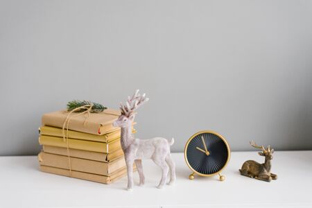Books, wrapped in Kraft paper, are stacked on a shelf, next to two figurines of a deer and a table clockの写真素材
