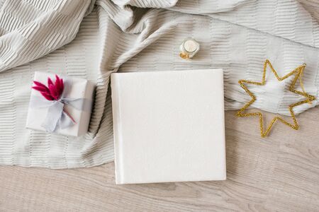 Leather cover with lace pattern of wedding photo book on wooden background and plaid with bright Christmas accessoriesの写真素材