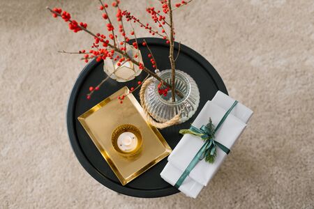 Top view of gift boxes tied with an emerald ribbon with a sprig of spruce, a candle, a vase of red berries and a gold tray. Lay flat, minimalistic concept of the blog. New Year, Christmas background.の写真素材