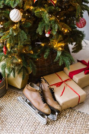 Old brown skates lie under the Christmas tree with giftsの写真素材