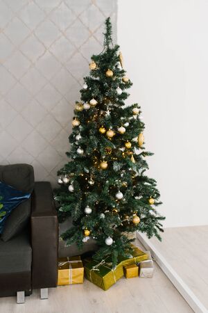 Christmas tree with white and gold balls with gifts under it in the living roomの写真素材