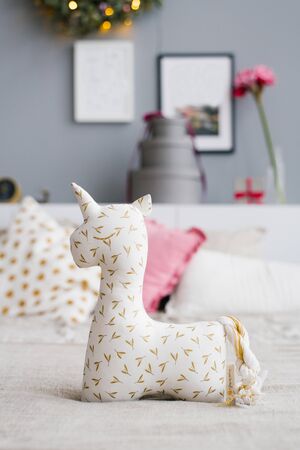 Soft toy or pillow in the form of a unicorn on the bed, decorated for Christmasの写真素材