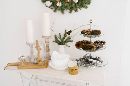 Christmas decor in white kitchen: candles, cones, spruce, plateの写真素材