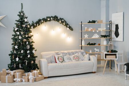 Living room decorated for Christmas, a sofa and a fir tree with lightsの写真素材