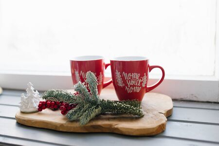Two red mugs on a wooden tray on the windowsill, Christmas decorの写真素材