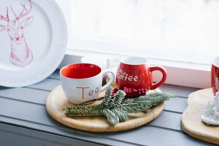 Two red mugs on a wooden tray on the windowsill, Christmas decorの写真素材
