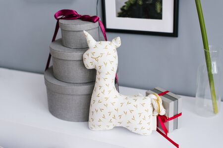 Unicorn soft toy for children and three round gift boxes tied with burgundy ribbonの写真素材