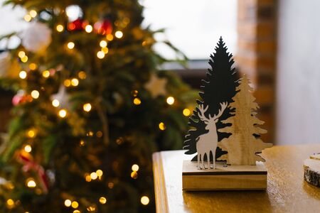 Wooden figurine deer and Christmas trees on the background of Christmas lights.の写真素材