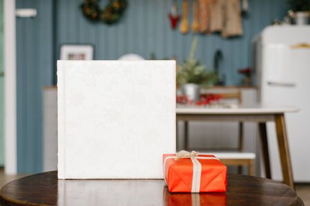 White wedding photo book with a leather cover with lace and a red Christmas gift box on the tableの写真素材