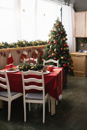 Traditional dining room decorated for Christmas and New Year, spruce with red and gold Christmas toys, table and chairs. Dinner tableの写真素材