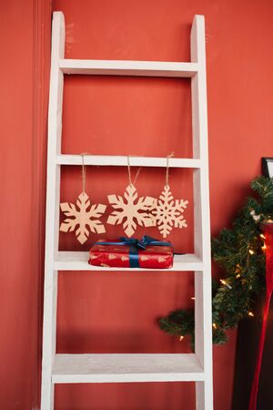 Christmas decor, white staircase, three snowflakes and a gift on the step against a red wallの写真素材