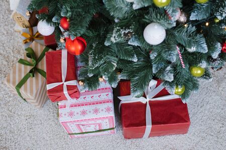 White and red christmas gift boxes with ribbons under the christmas treeの写真素材