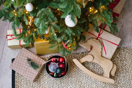 Christmas gifts, wooden rocking horse toy and Christmas tree toys in box under Christmas tree, top...
