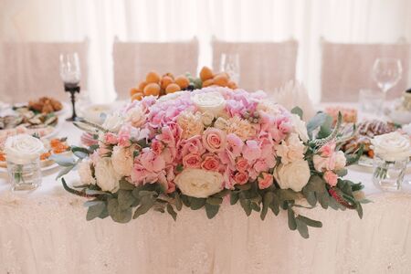 Floral arrangement of pink hydrangea, roses and eustom on the Banquet festive table of the bride and groom in pastel colorsの写真素材