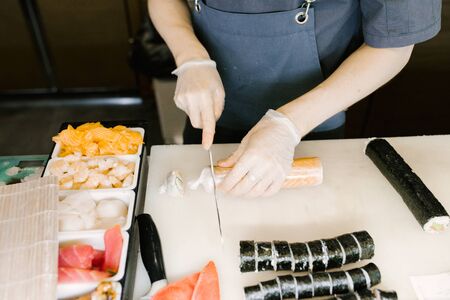 Chef cuts sushi with a knife, cooking Japanese sushi in a restaurant man, close-upの写真素材