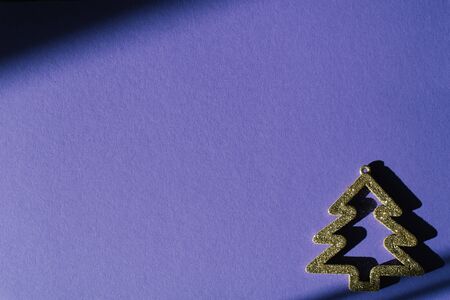 Creative greeting card for New Year or Christmas. Gold Christmas tree on purple background with glitter and shadows. Copy space. Flat layの写真素材