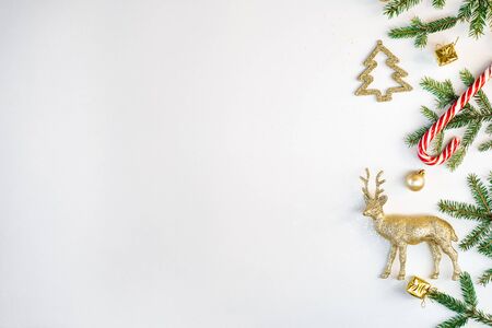 New year and Christmas composition. Border frame of gold Christmas toys, fir branches, deer on a white paper background. The view from the top, flat position, where you want to copy. Holiday cardの写真素材