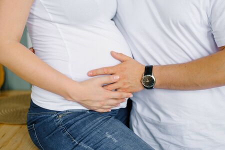 The future father holds his hand on the stomach of the future mother, his pregnant wife. Expectant...