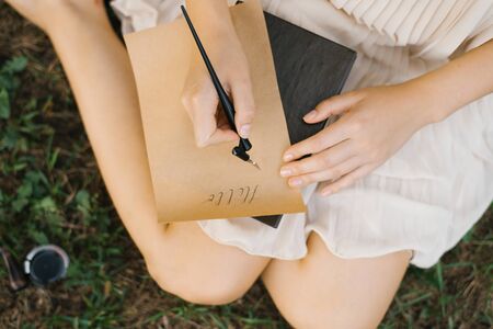 Girl writes pen and ink on Kraft paper letter. Close - up of hands. Romance. Calligraphyの写真素材