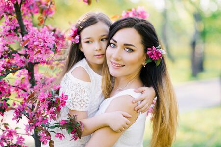 Mother and daughter in the blooming rose gardens of Apple trees. Happy motherhood. Beautiful family portraitの写真素材