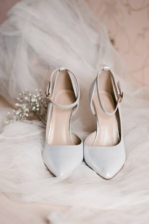 Light gray shoes for the bride are on the veil and there is a sprig of gypsophila next to it. Accessories for the bride for the weddingの写真素材