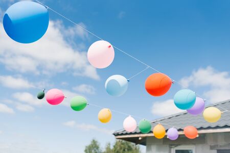 Bright balloons hang on a string in a row against the blue sky. Outdoor holiday decorの写真素材
