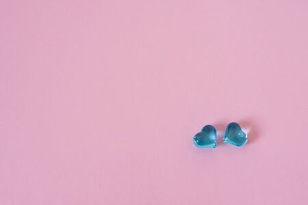 Two blue glass hearts on a pink background with copy space Creative background or Valentine's day...