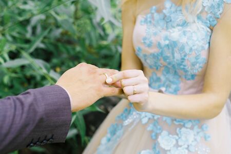 The bride puts a wedding ring on her finger to the groom. Large view of hands