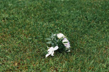 A lilac and beige wedding bouquet lies on the green grass.Copy space.の写真素材