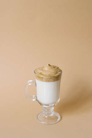 Beautiful dalgon drink coffee with foam in a transparent mug on a beige backgroundの写真素材