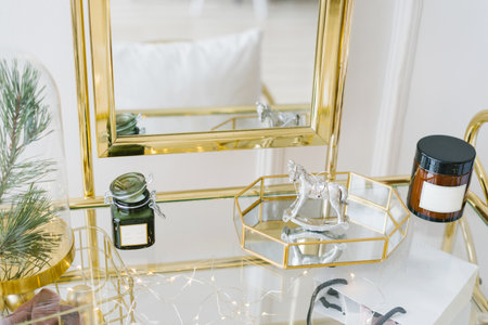 Decor on the boudoir table of a young woman in the bedroom: candles, a mirror, a glass tray, a...
