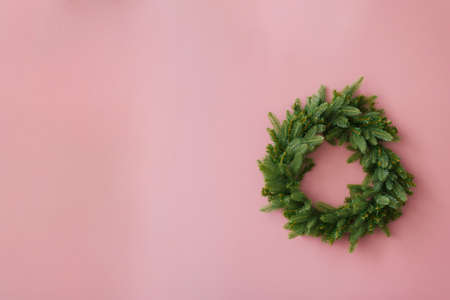 Christmas wreath of fir branches on a bright pink background with a copy spaceの写真素材