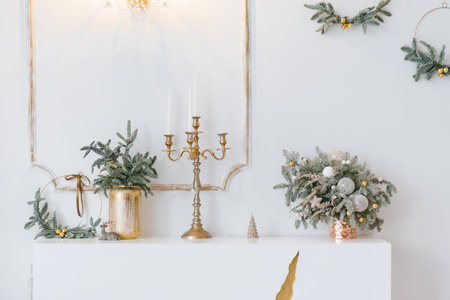 Christmas decor in a classic living room or bedroom in bright colors. Spruce branches in gold vases with toys and a gold candlestick on the dresserの写真素材