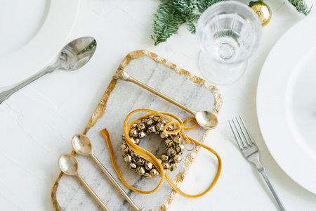 Christmas wreath of Golden bells in the decoration of the festive dinner. Cutlery on a marble Boardの写真素材
