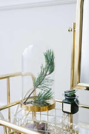 Christmas decor: pine branches in a glass flask on the table, a candle in a jar with green glassの写真素材