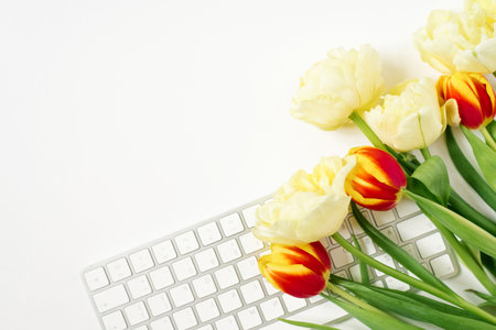 Flat lying Valentine's Day background with computer keyboard and tulip bouquet. Top view. white space for copyingの写真素材