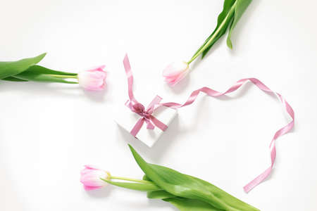 Spring pink tulip flowers and gift box on white background from above in flat lay. Congratulations on Women's Day or Mother's Day.の写真素材