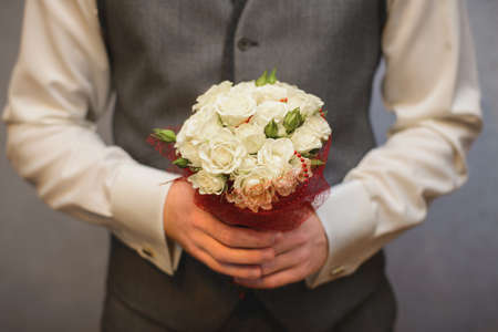 wedding small cute bouquet of white roses in the hands of the groom