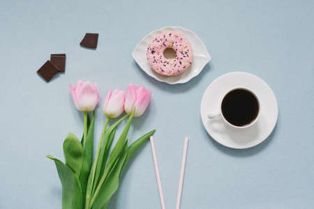 Pink donut on a saucer, pink tulips and coffee on a blue background. Romantic Valentine's day Breakfast in bed for your loved one. The concept of mother's Day, 8 March. The view from the top. Ð¡opy space.の写真素材