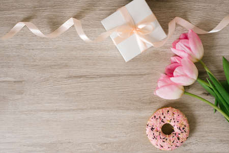 Tulips, gift box and coffee on a wooden background, space for text. Flat lay. 8 March, International...