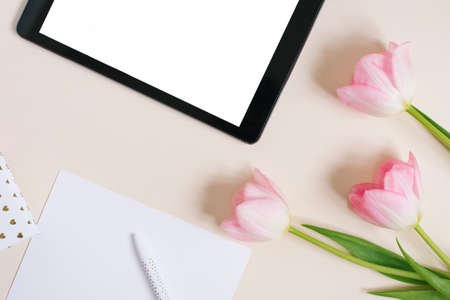 Flat flat top view mock up: digital tablet and pink tulips on beige background. Copy space and flat lay. The concept of the blog for spring, Mother's day, Valentine's dayの写真素材