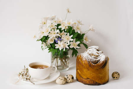 Easter sweet bread, cake and eggs with white apple flowers and primroses, a cup of tea. Festive...