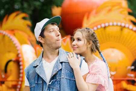 Happy couple in love having fun in an amusement park, eating lollipops