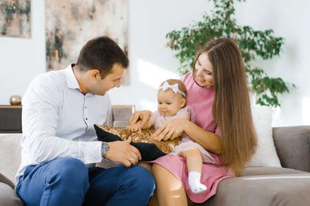 Happy young family with one year old girl playing in the living room of their new home
