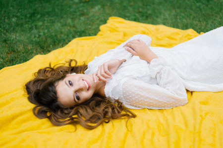 Top view young woman on a picnic, lying on a blanket. She is happy and smiles a dazzling smileの写真素材