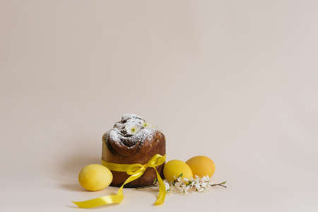 Easter composition of sweet bread cake, white flowers and yellow eggs on a light background....