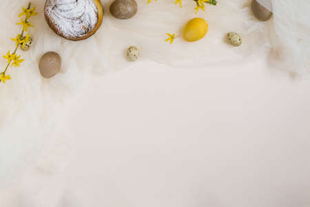 Easter cake, eggs, forsythia branches on a beige background. Copy space, flat lying. Easter concept