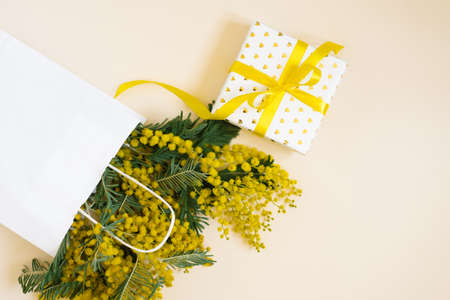 Yellow mimosa flowers frame with gift box. Womans day, easter, spring composition. Top view with copy spaceの写真素材